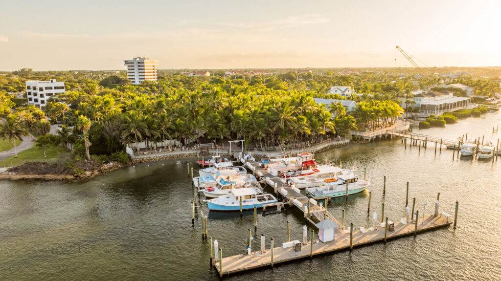 Wide sunrise photo with Castaways Marina, fuel dock, and intracoastal waterway in the foreground and Square Grouper Tiki Bar Jupiter Inlet in the background