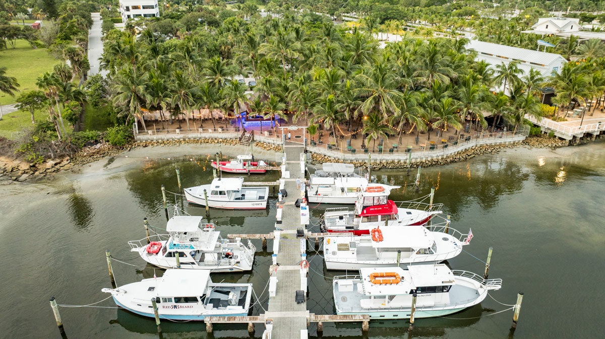 Wide Aerial photo of Castaways Marina with several boats docked and the Square Grouper Tiki Bar in the background