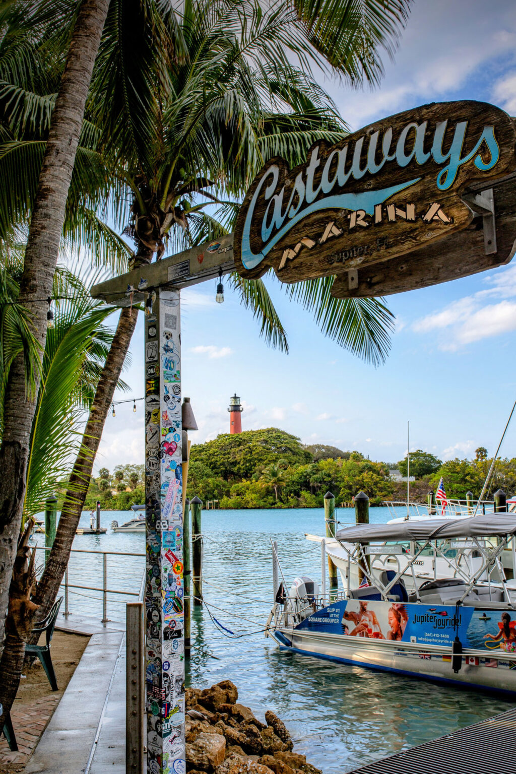 Castaways Marina sign with boats in the foreground and Jupiter Lighthouse in the background